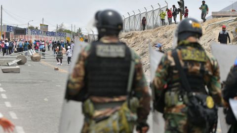 نیروهای امنیتی که در تصویر در 4 ژانویه 2023 به تصویر کشیده شده اند، در کنار آوارهای به جا مانده توسط معترضانی که تلاش می کنند کنترل شهر آرکیپا در آند پرو را در دست بگیرند، ایستاده اند. 